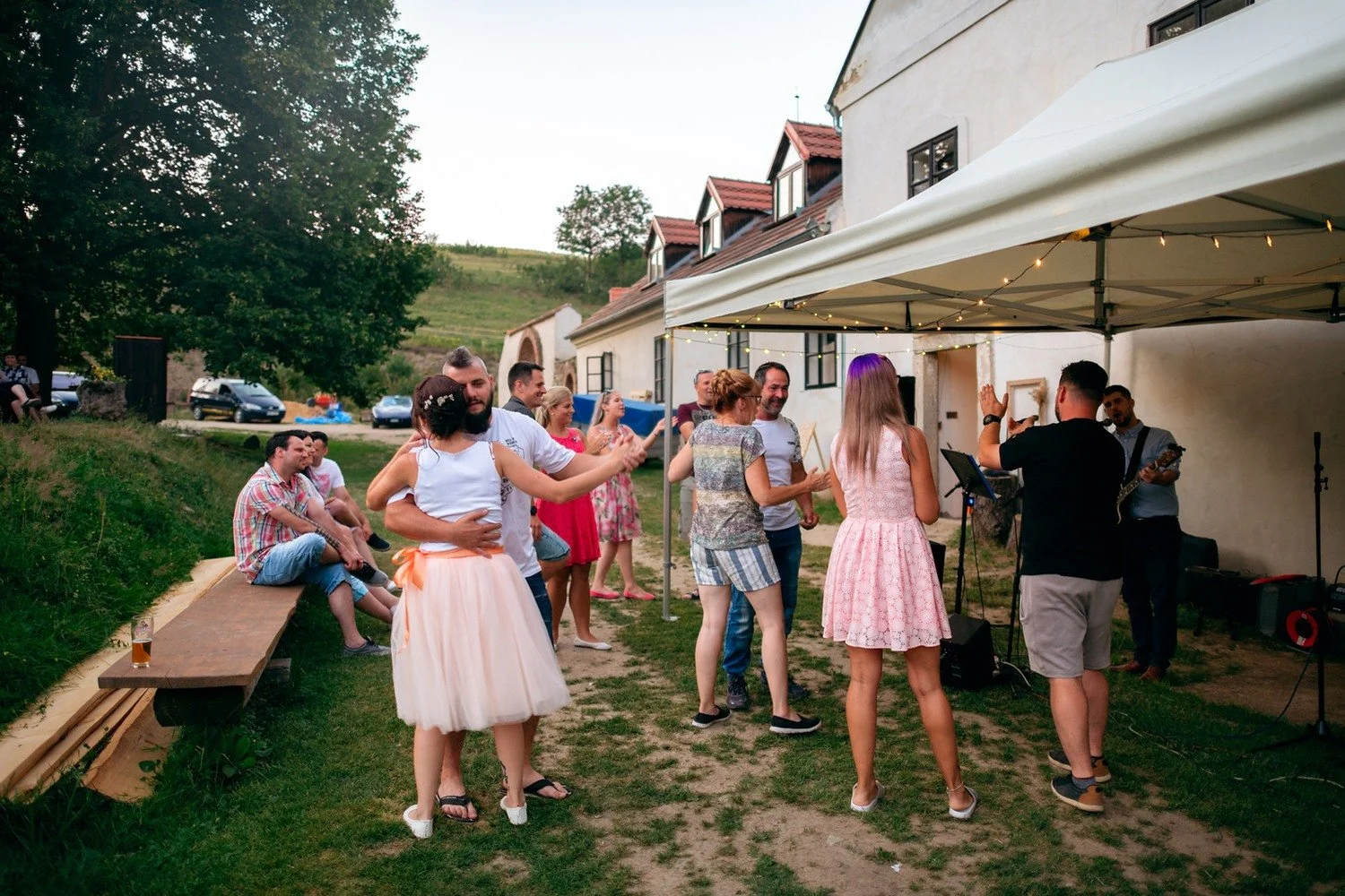 Hosté tančí před bílým stanem, ve kterém hraje živá kapela.