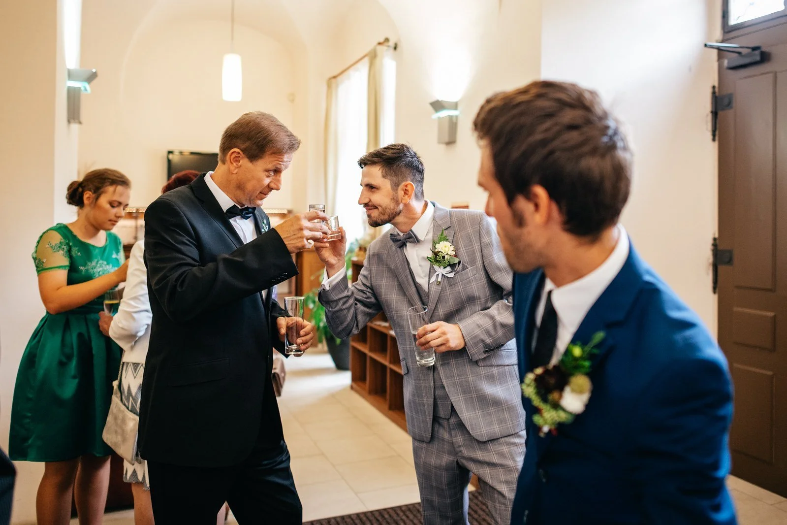 Skupina mužů stojí společně před vstupem do budovy.