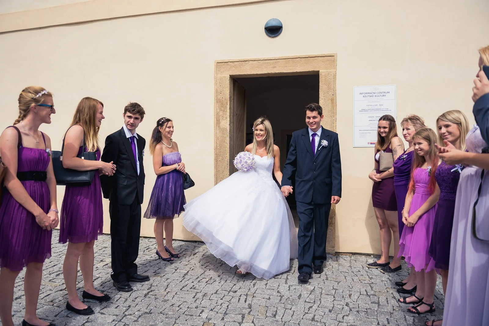 Novomanželé vycházejí ze zámeckých dveří špalírem svatebčanů a Ivana si nadzvedává sukni.