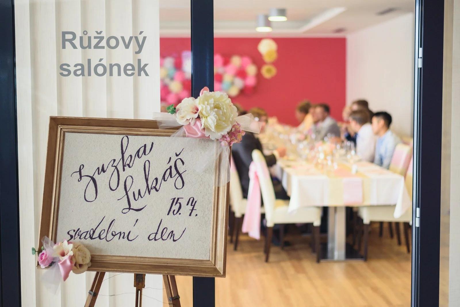 Tabule se svatebním obědem vítá hosty u vstupu do růžového salonku.