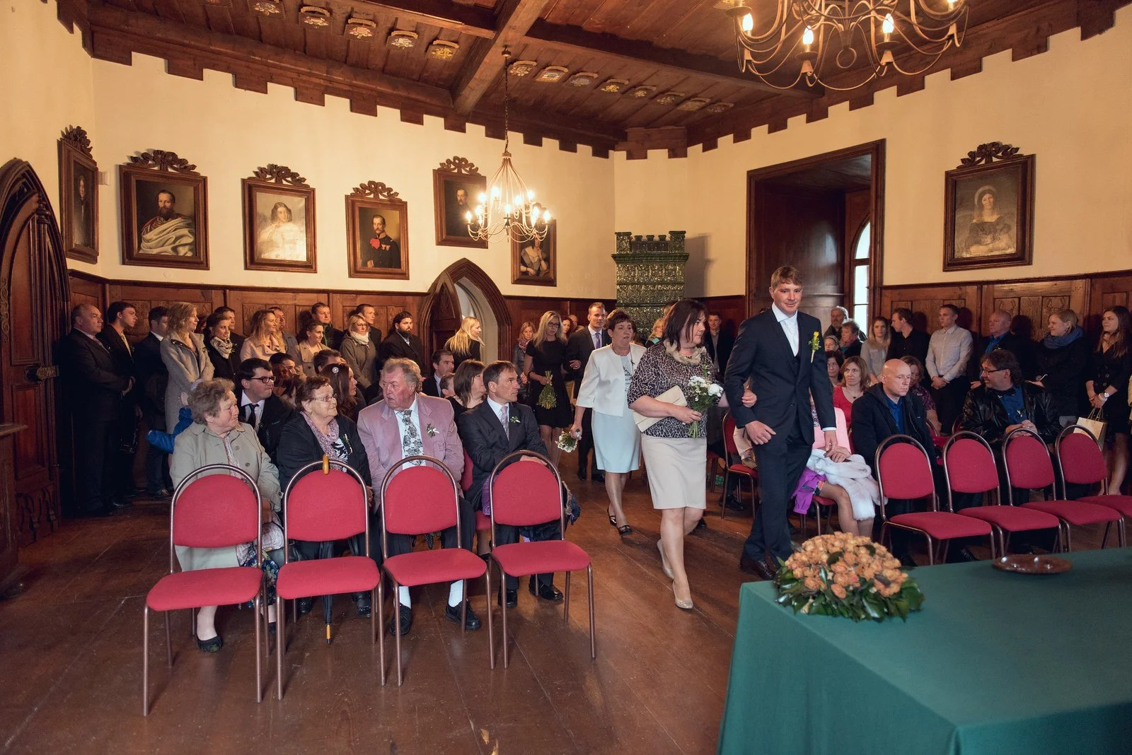 Hosté stojí v řadách po obou stranách uličky v obřadní síni.
