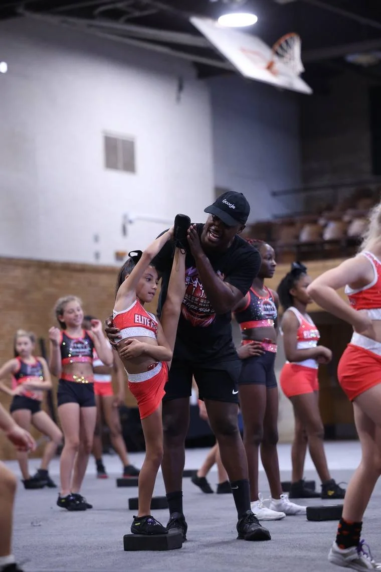 Coach Malek Hinton helping a flyer with her heel stretch