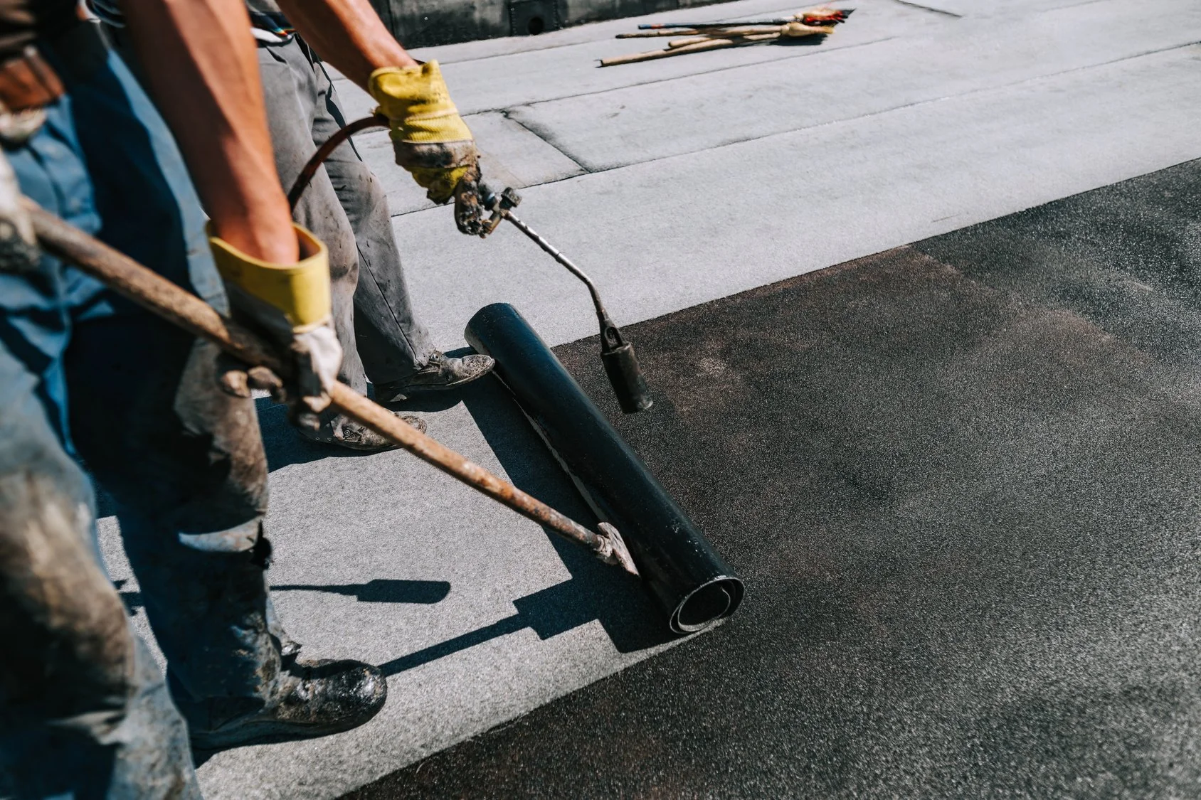Workers applying bituminous membrane on a flat roof