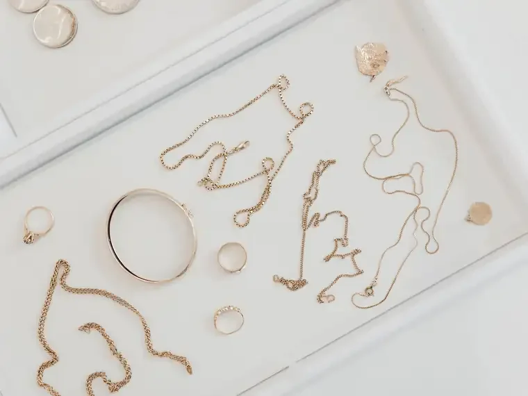Gold chains, rings and a bangle laid out on a white tray