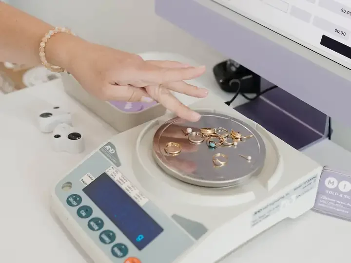 A buyer places gold jewellery on a precision scale