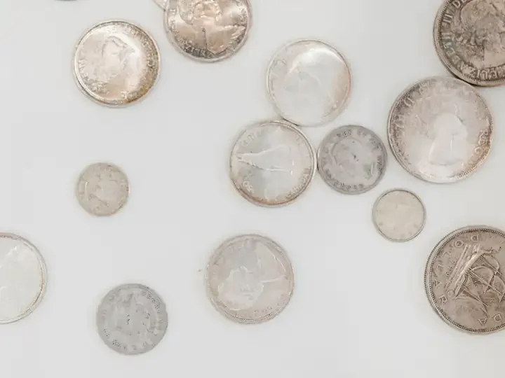 Silver coins scattered on a white surface