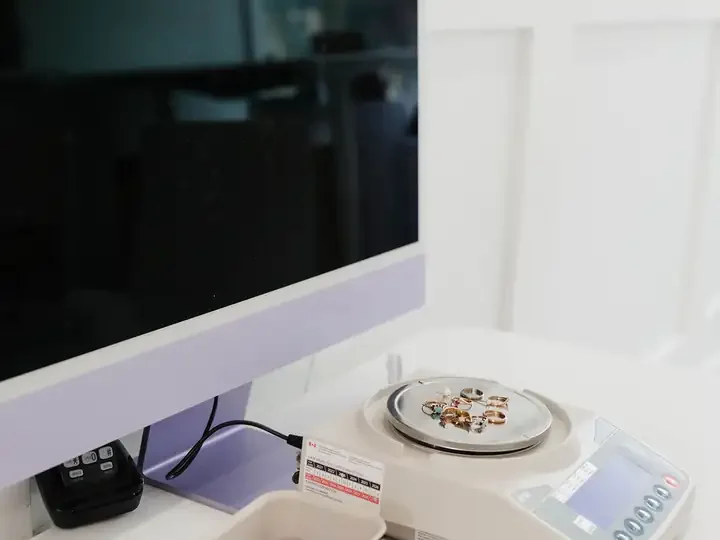 A precision scale and a karat sorting tray beside a computer at the testing desk