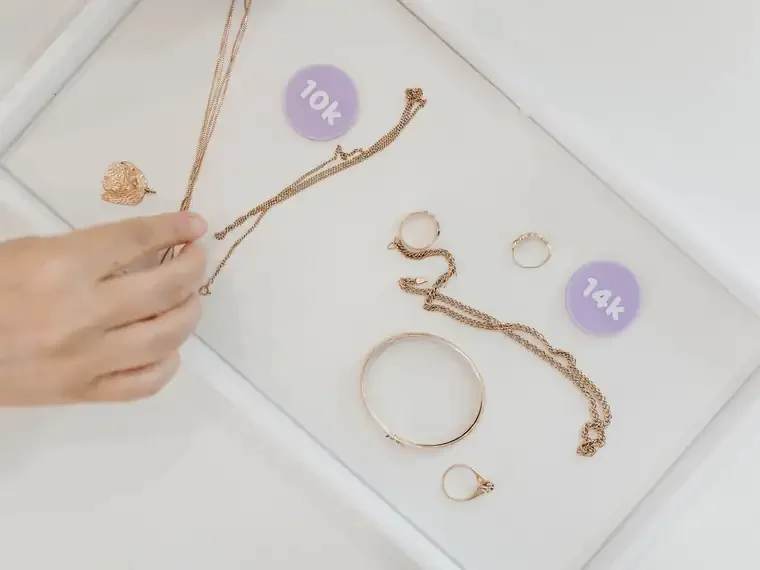 Gold chains, rings and a bangle sorted by karat on white trays labelled 10k and 14k