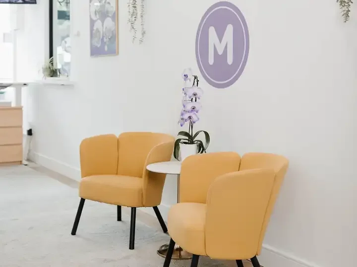 Yellow lounge chairs and an orchid under the MINTY logo in the shop
