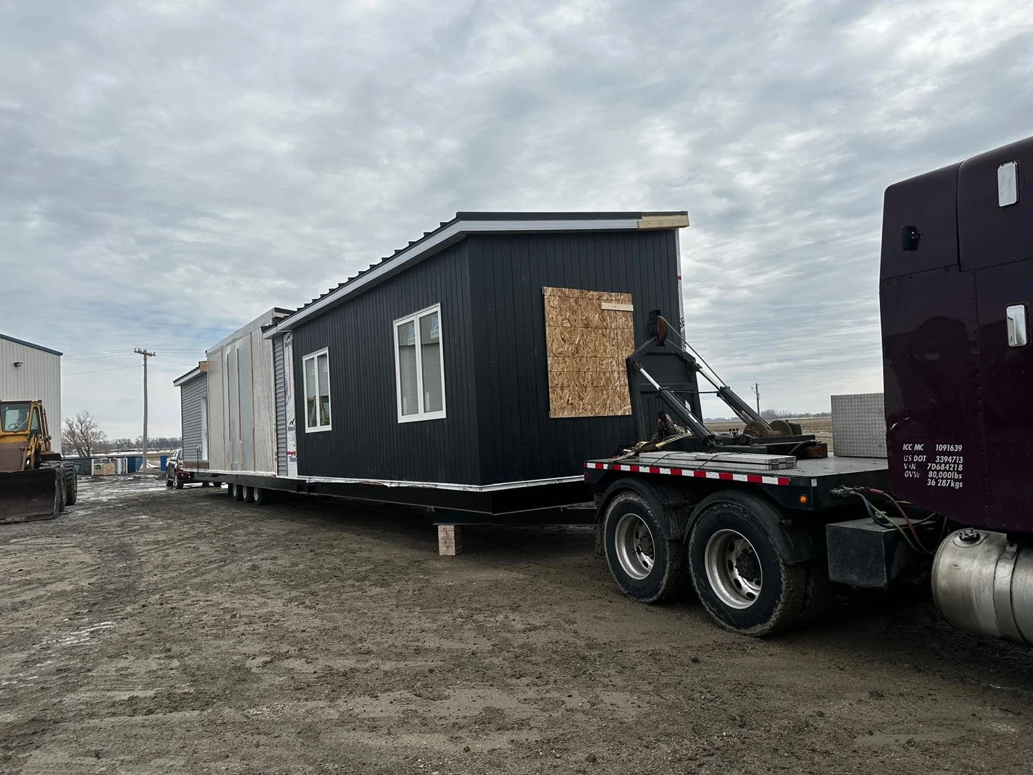 A black ready-to-move house loaded on a trailer