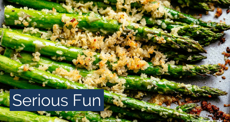 A close-up of asparagus covered with parmesan cheese. The text says "Serious Fun."