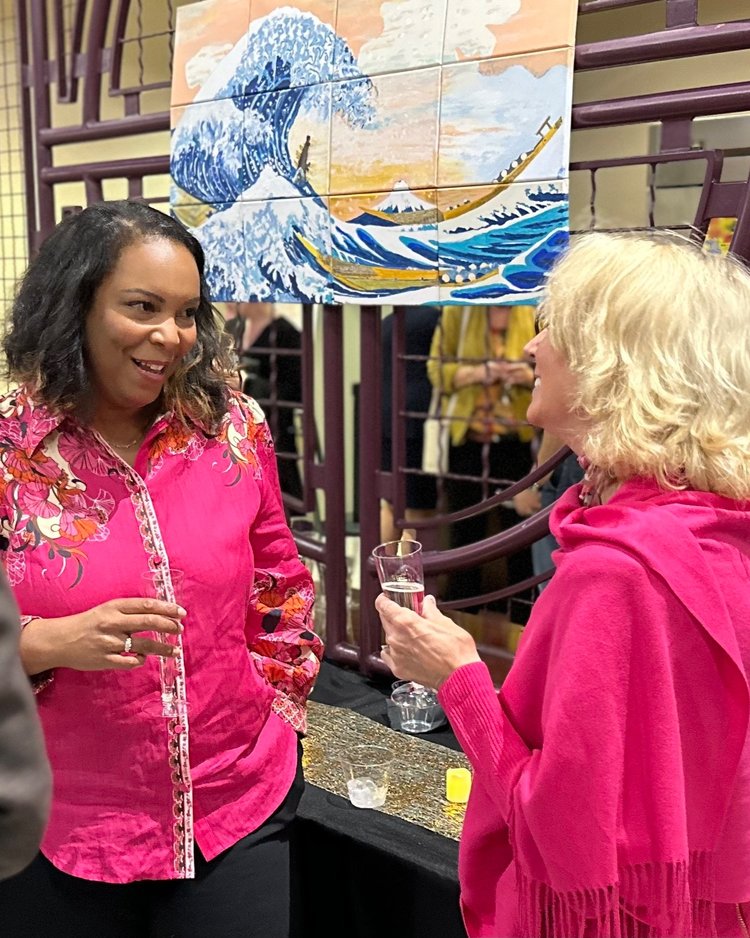 Two women wearing pink are talking to each other.