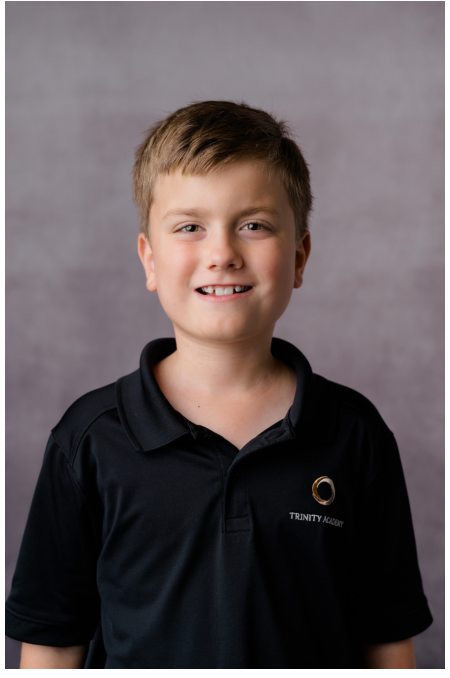 Student smiling for a school portrait against a gray background.