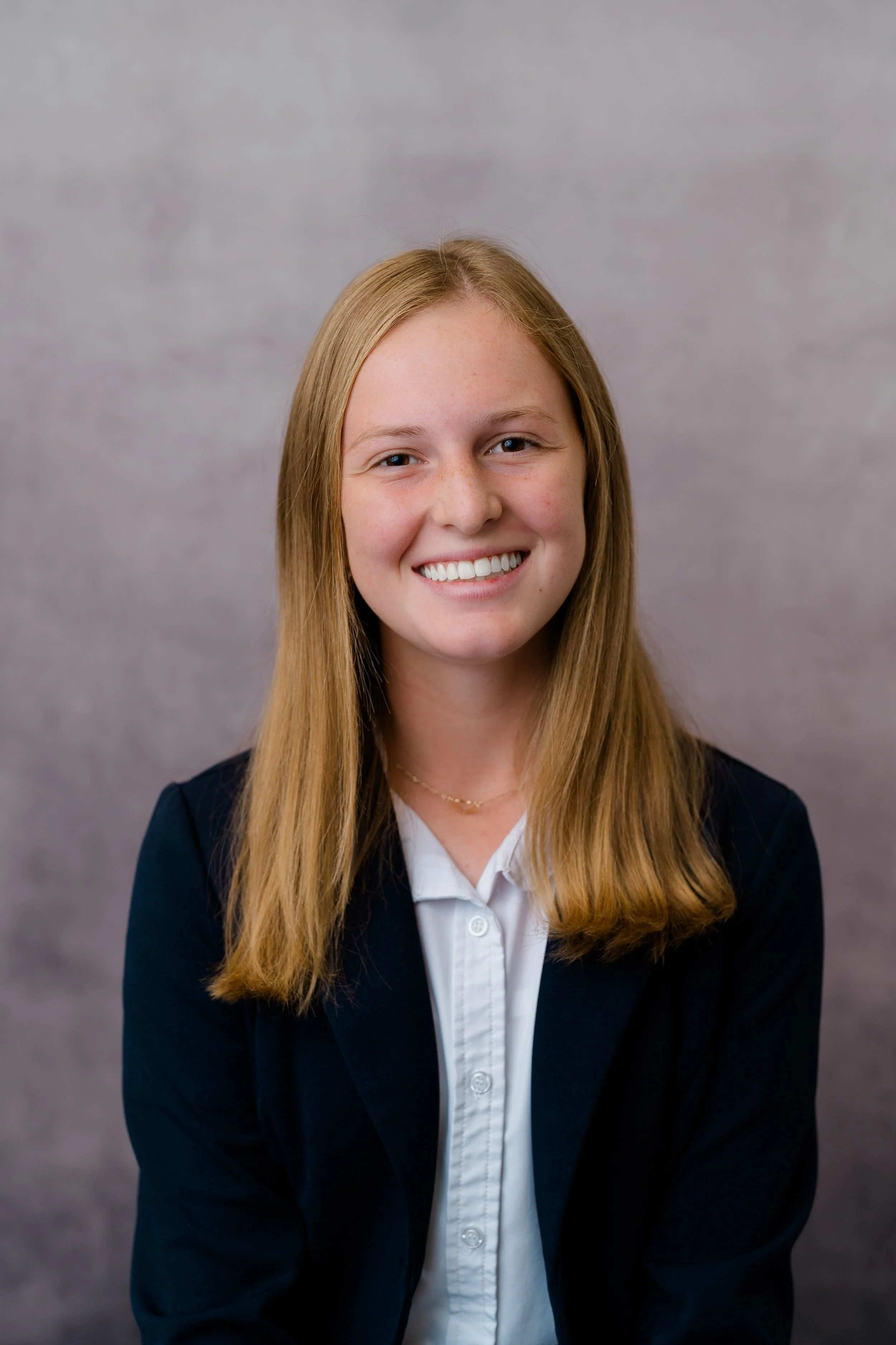 Student smiling for a school portrait against a gray background.