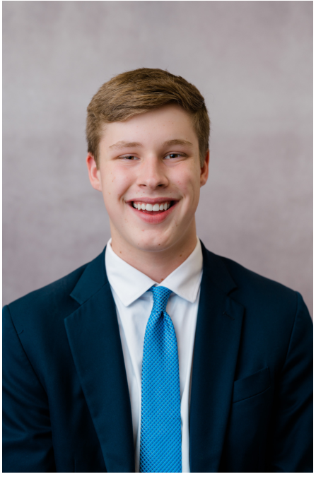 Student smiling for a school portrait against a gray background.