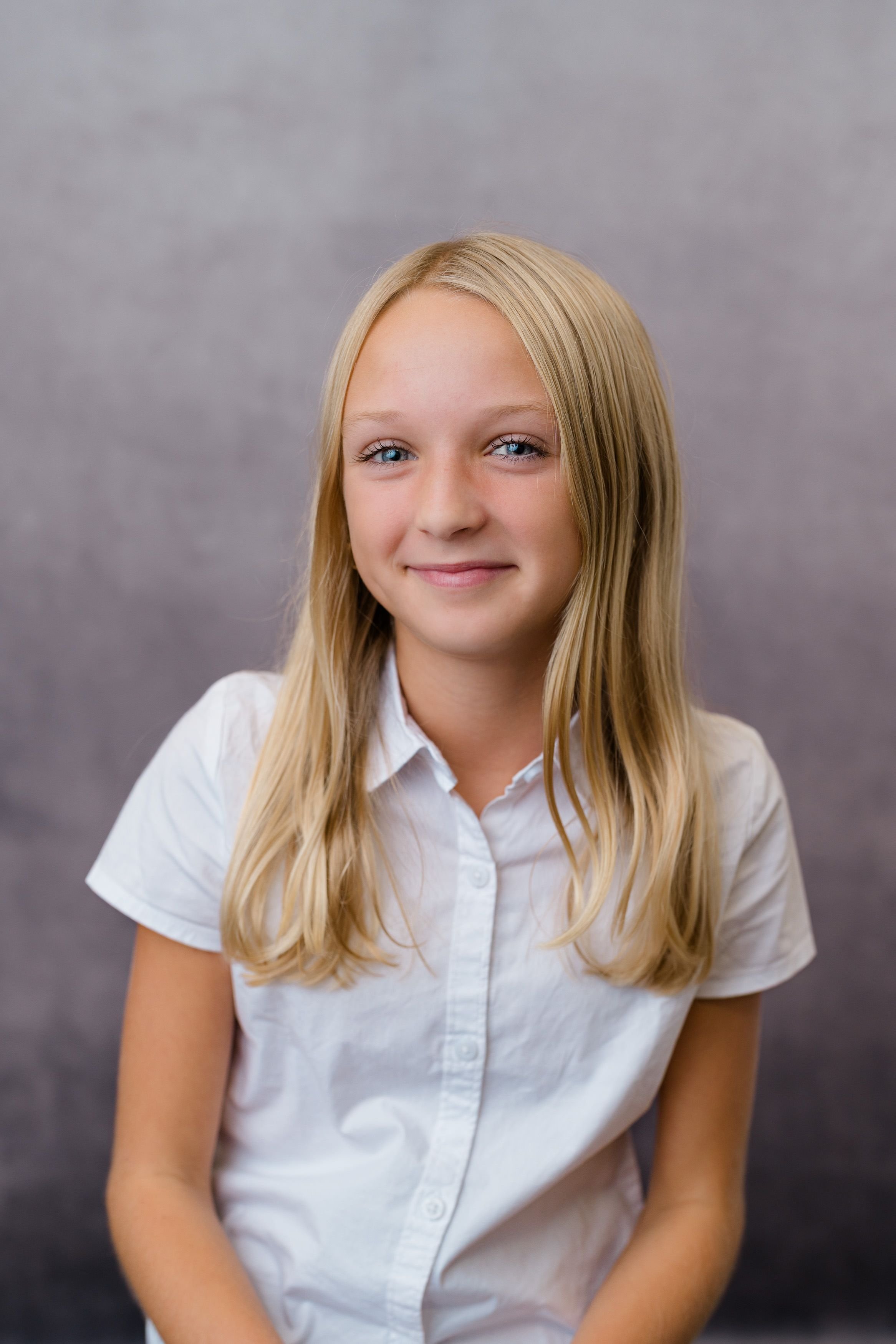 Student smiling for a school portrait against a gray background.