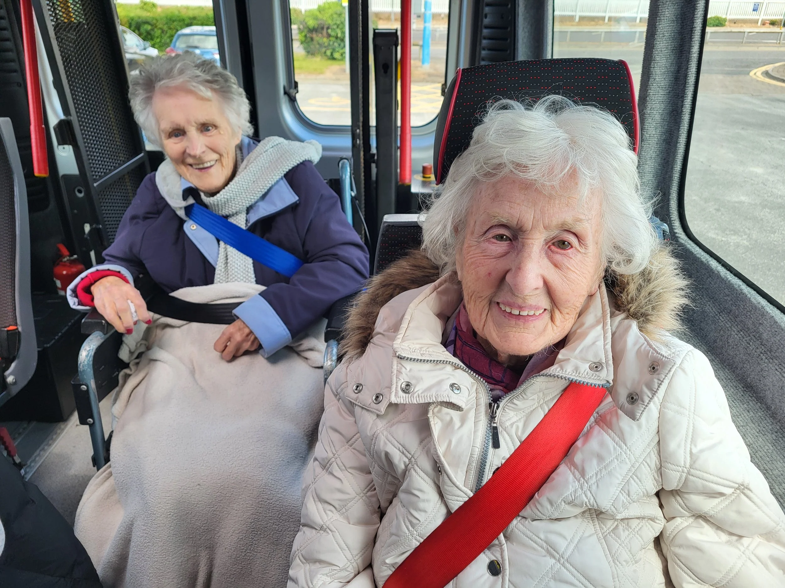 Two residents from The Abbeys Care Home smiling on the minibus
