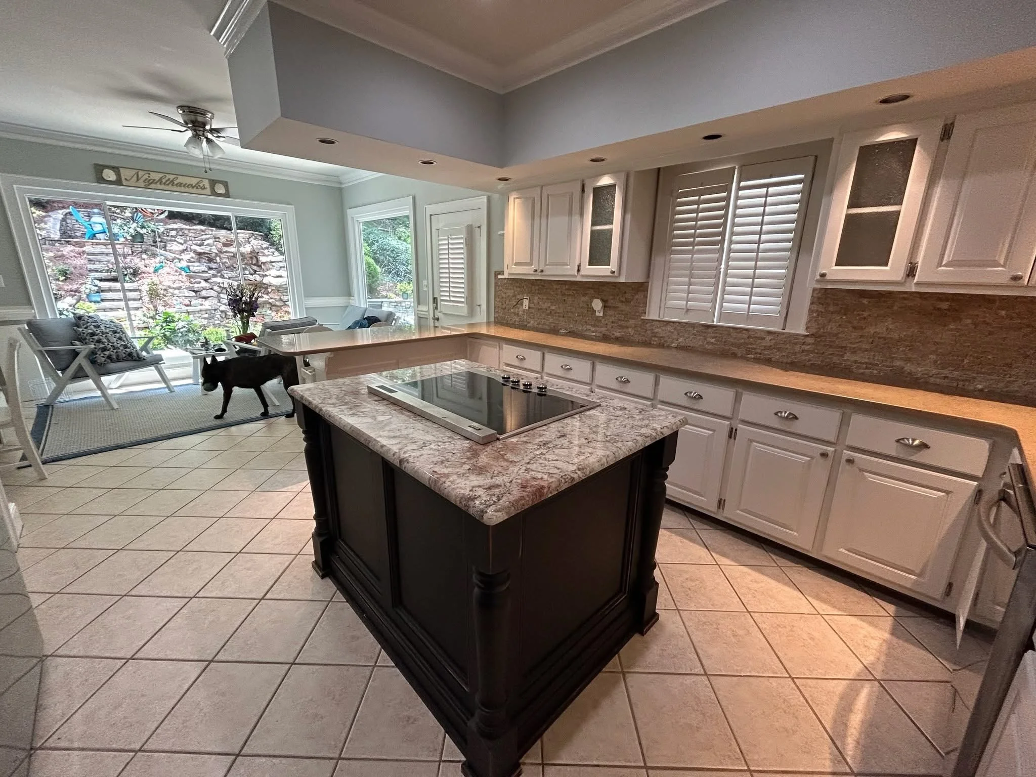Finished white painted kitchen cabinets in a Roswell home, viewed from the island toward the sunroom