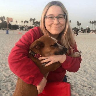 Image of employee Madison holding a dog on a beach
