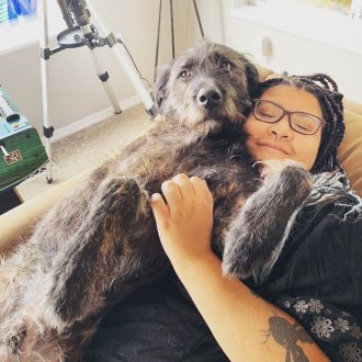 Image of employee Hailey and a dog laying on Hailey’s chest