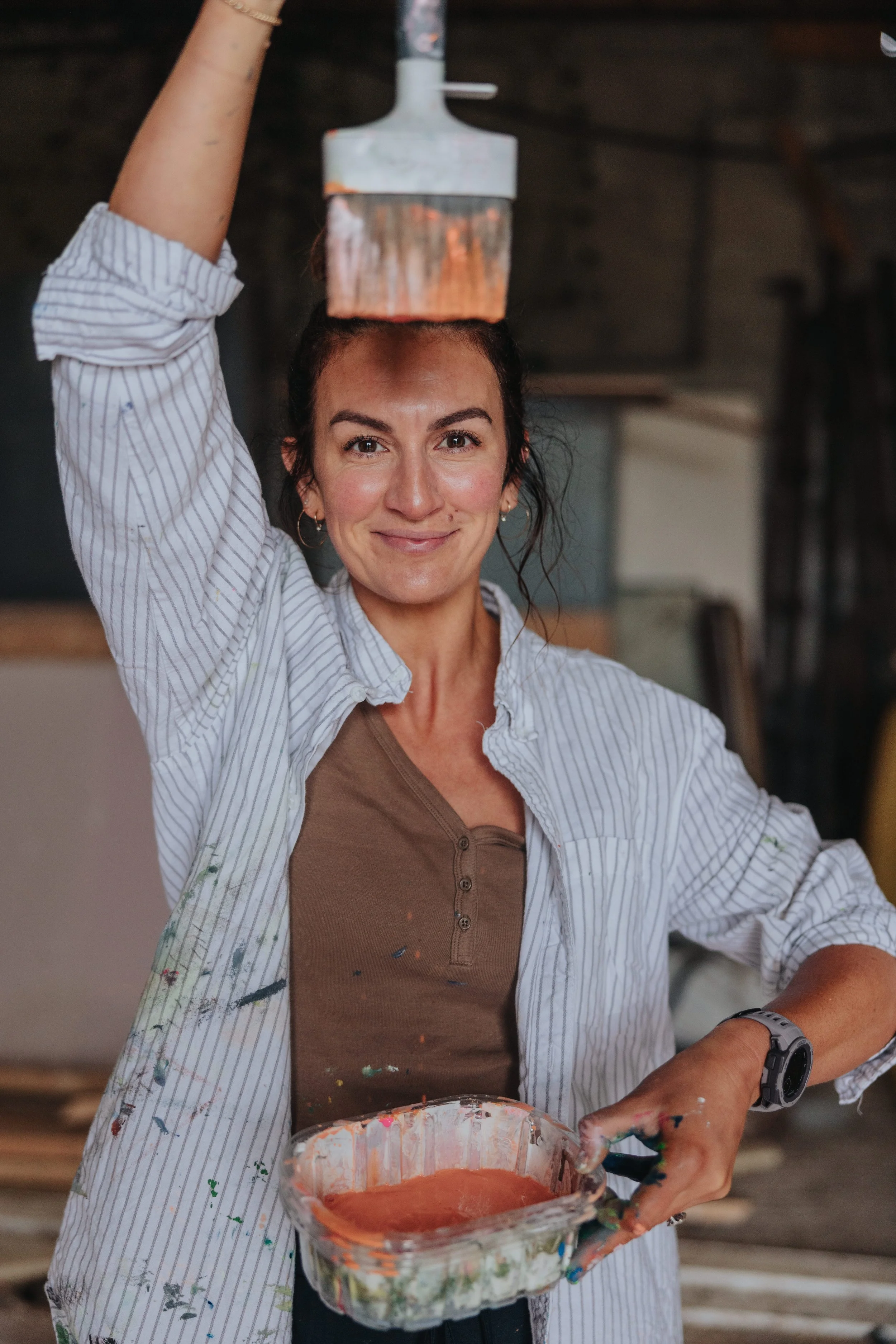 Aly Harte holding her paintbrush in the studio