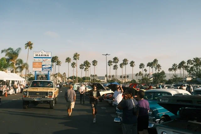 Crowd walking through an outdoor car show.