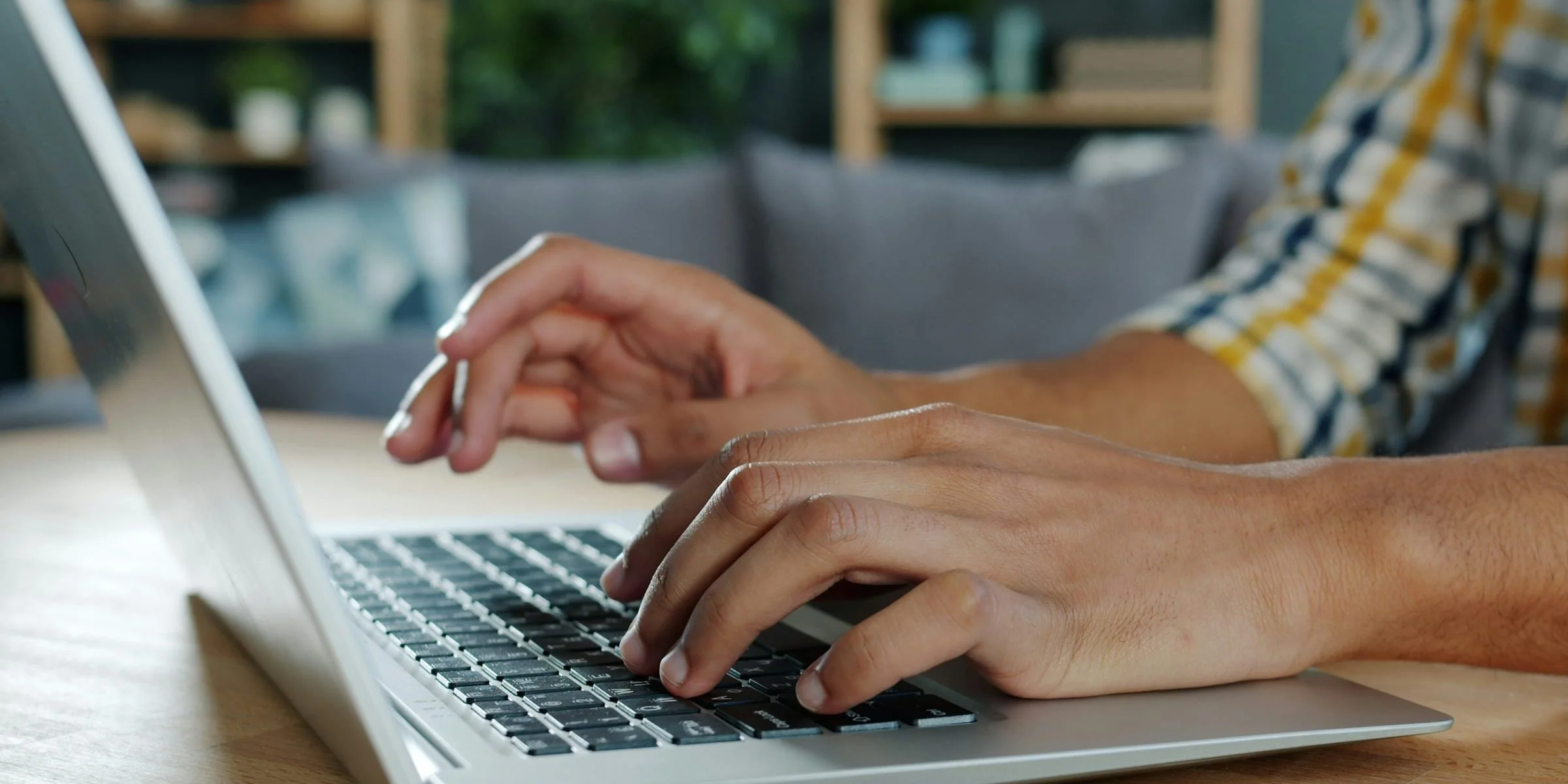 Hands typing on a laptop at a home desk.