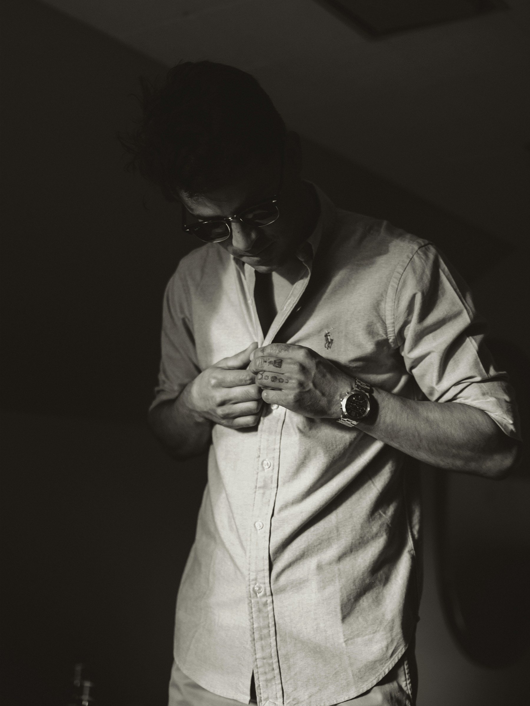 Man fastening the buttons of a long-sleeve shirt.