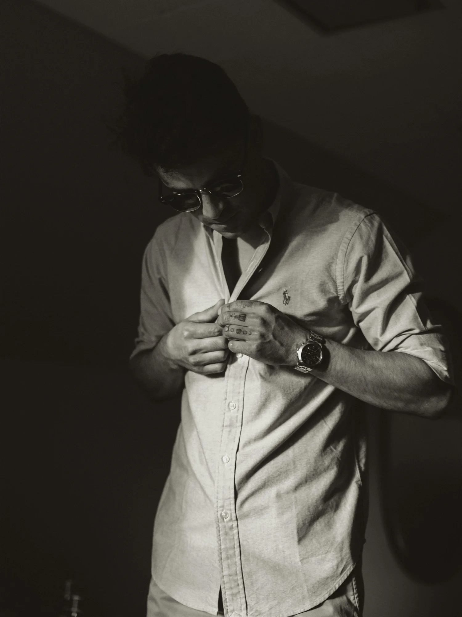 Man fastening the buttons of a long-sleeve shirt.