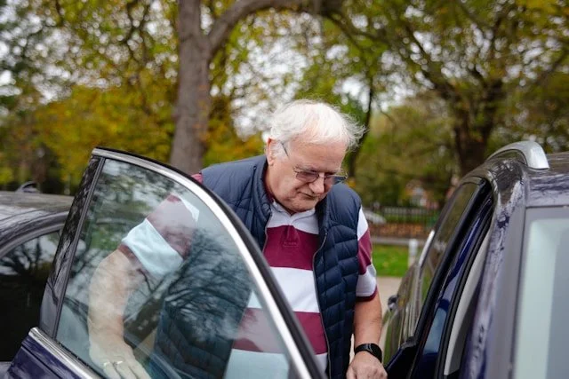 Older man practices getting into a car during hip-replacement recovery