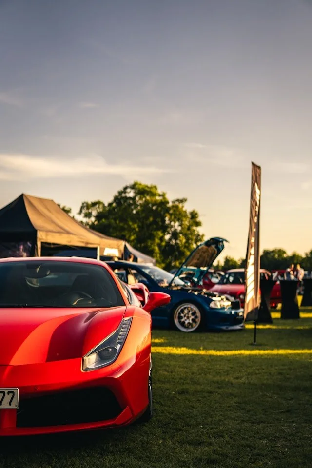 Red Ferrari displayed at a busy outdoor car show.