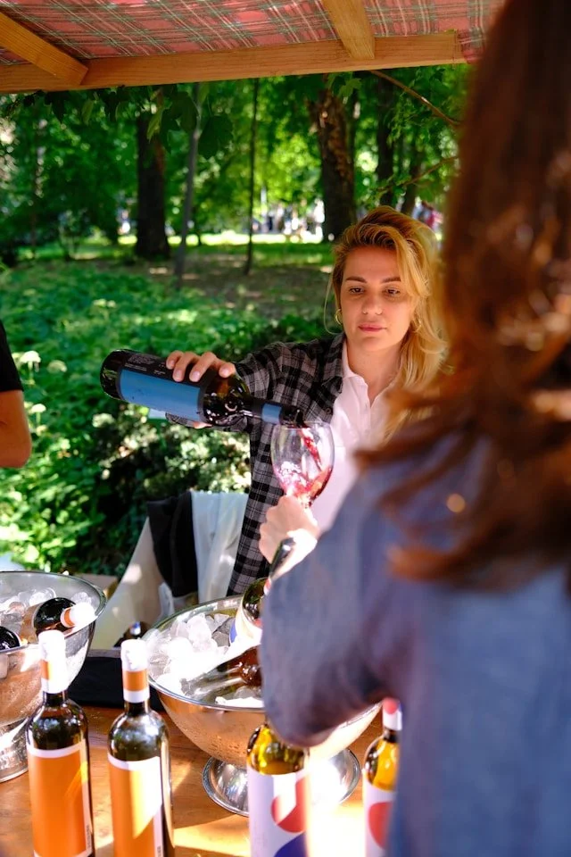 Woman enjoying a glass of wine at an outdoor event, used as an illustrative festival scene