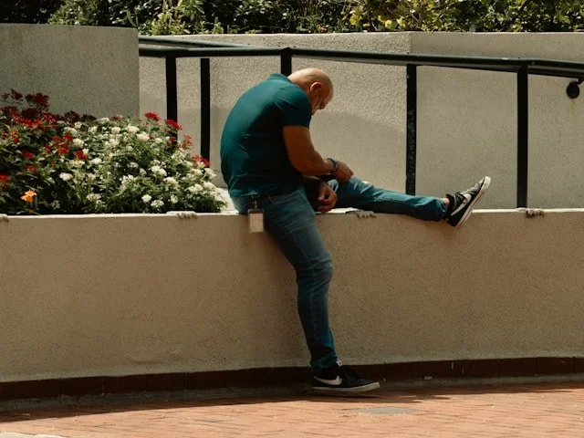 Man stretches his leg while seated outdoors