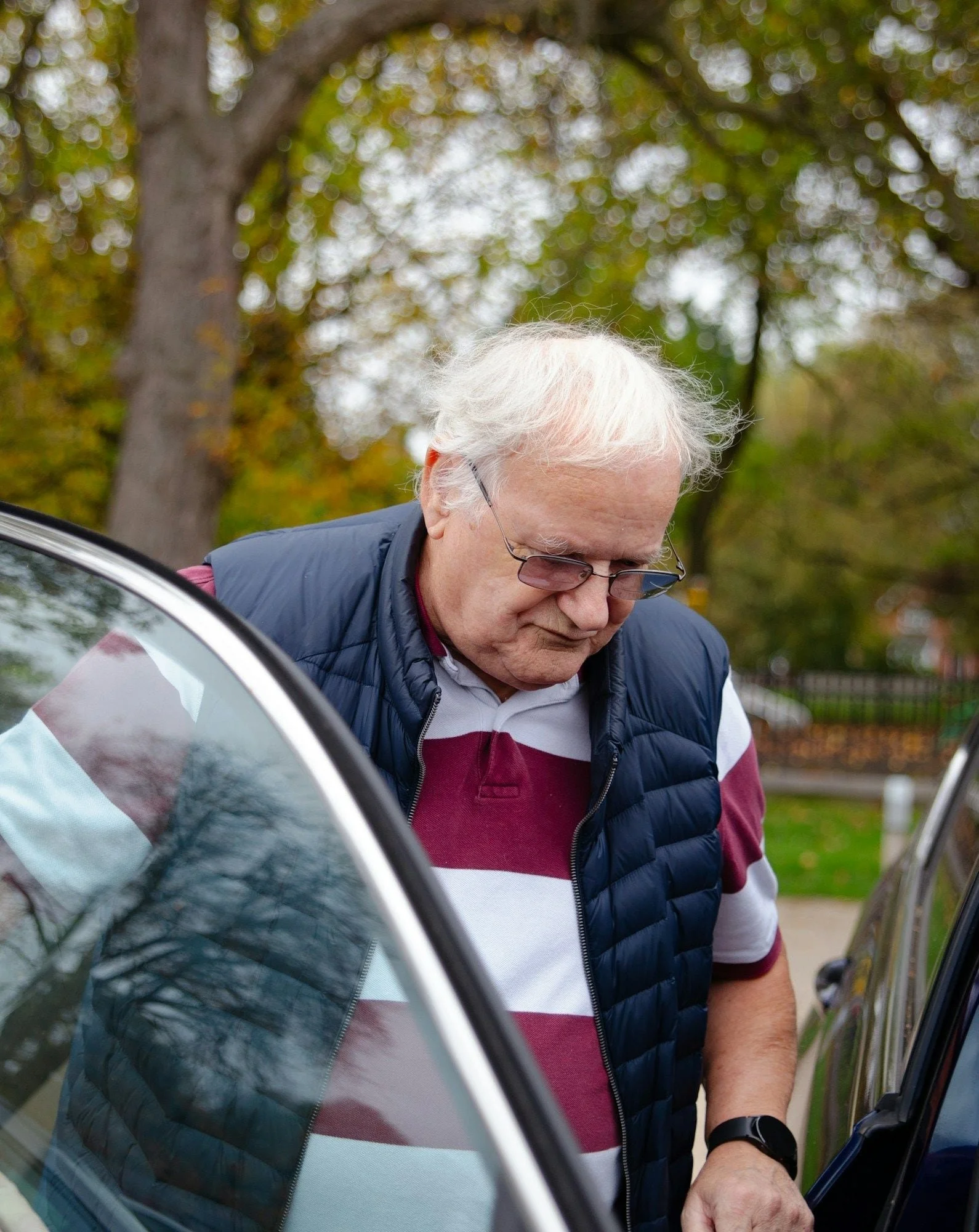 Older man getting into a parked car.