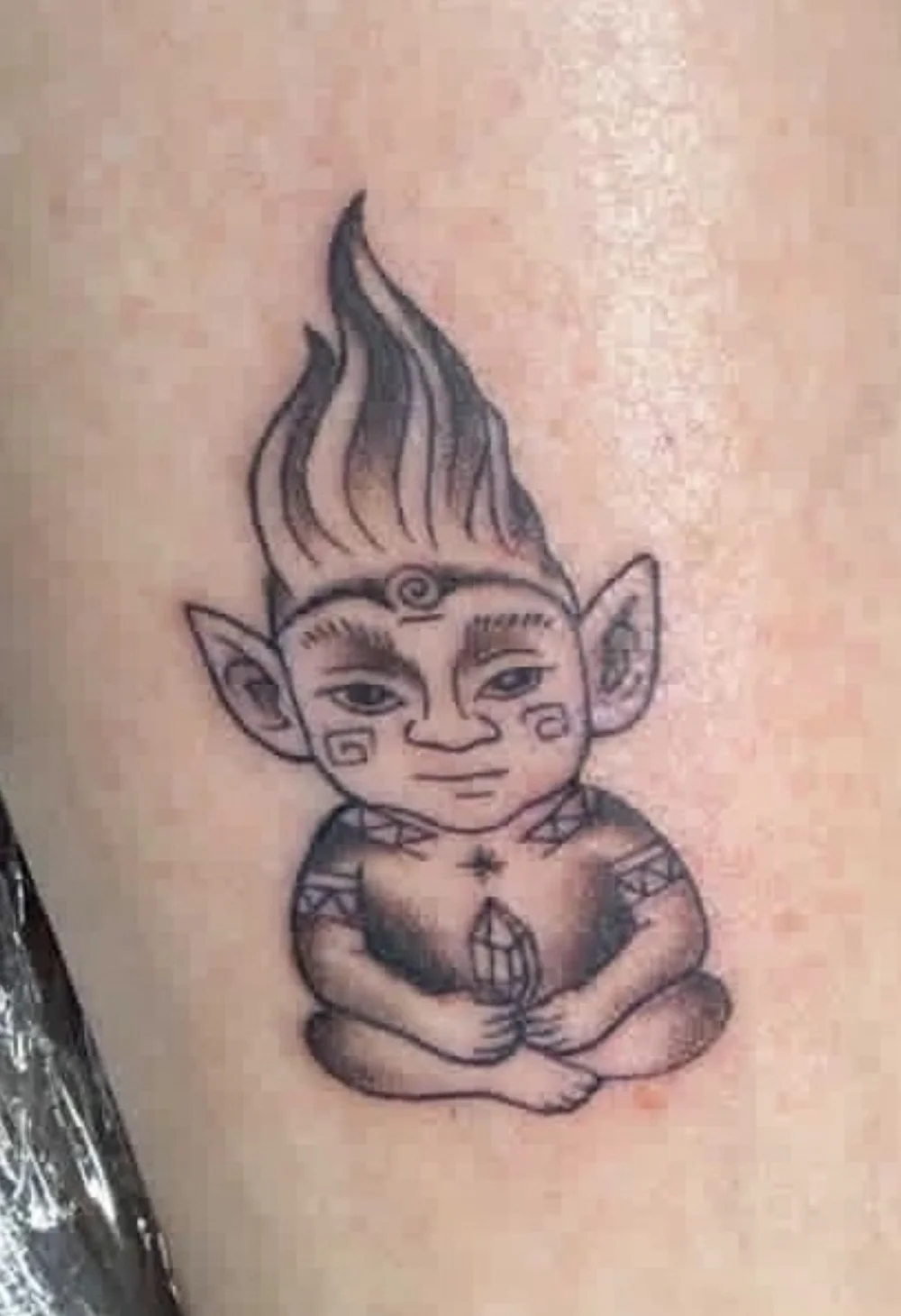 the finished troll tattoo holding a crystal, with her father's ashes in the ink