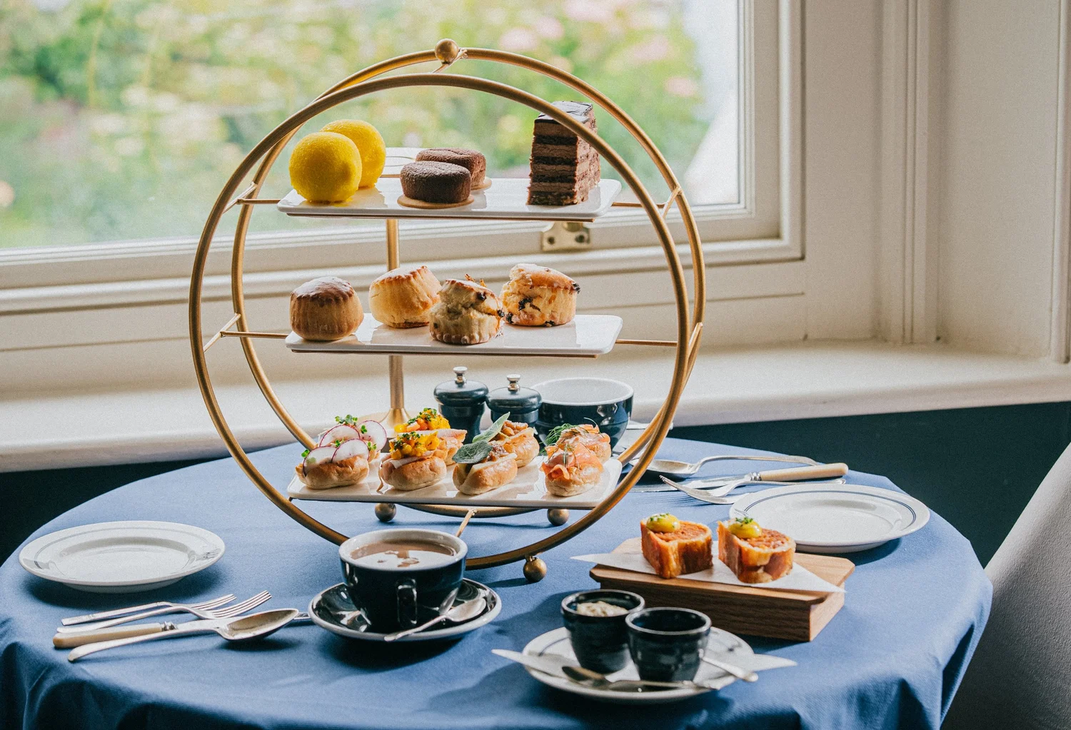 Afternoon tea with pastries, scones and sandwiches by the window