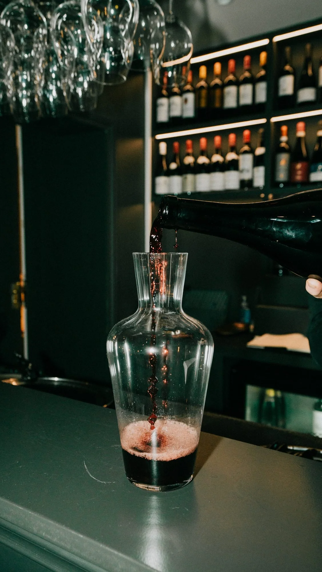 Red wine being decanted into a carafe at the bar