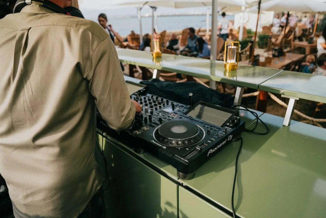 A DJ setup on the outdoor kitchen counter with guests gathered behind