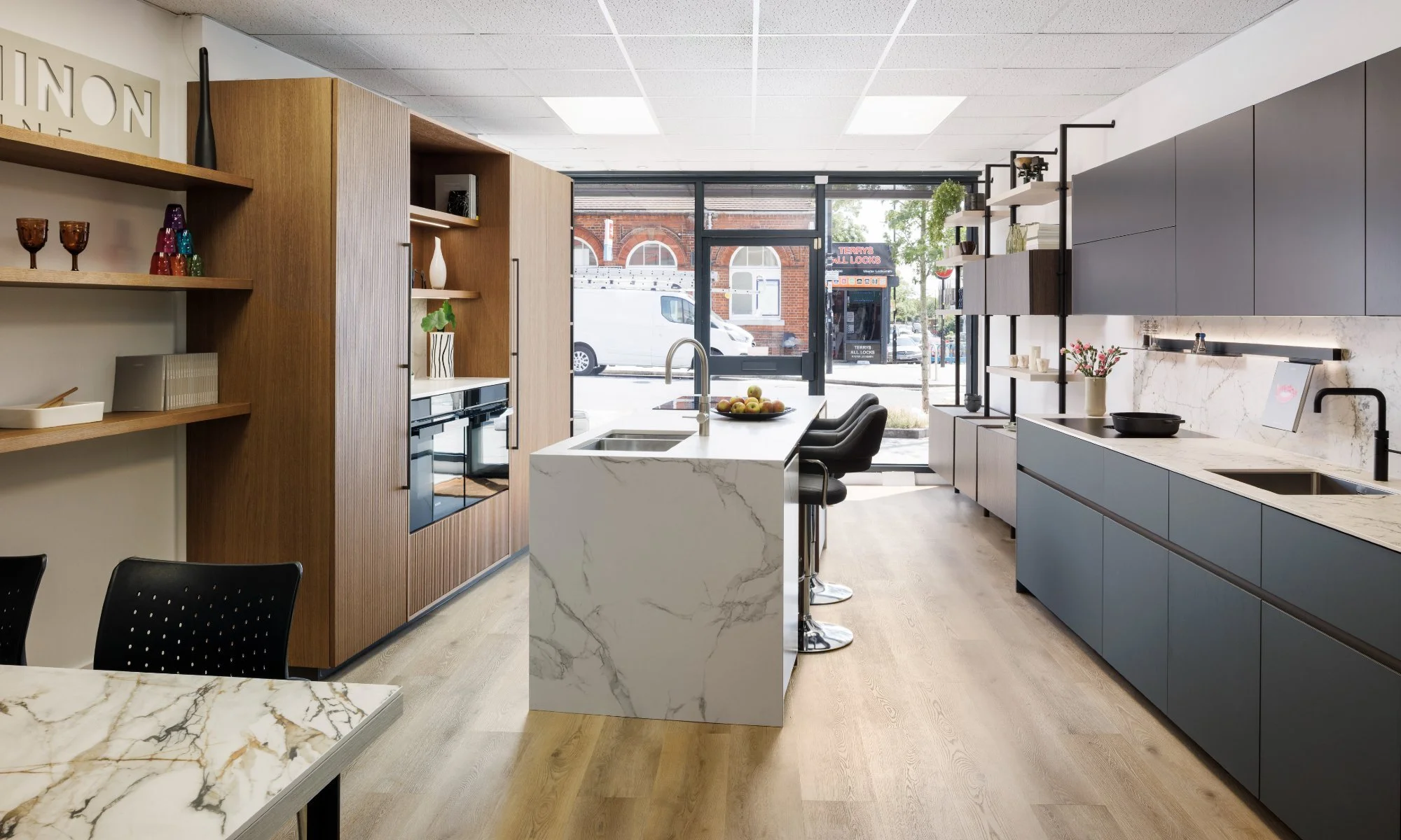 Puccini showroom looking down the length of the room towards the shopfront on Brockley Road, showing cabinetry runs, worktops and the design table.