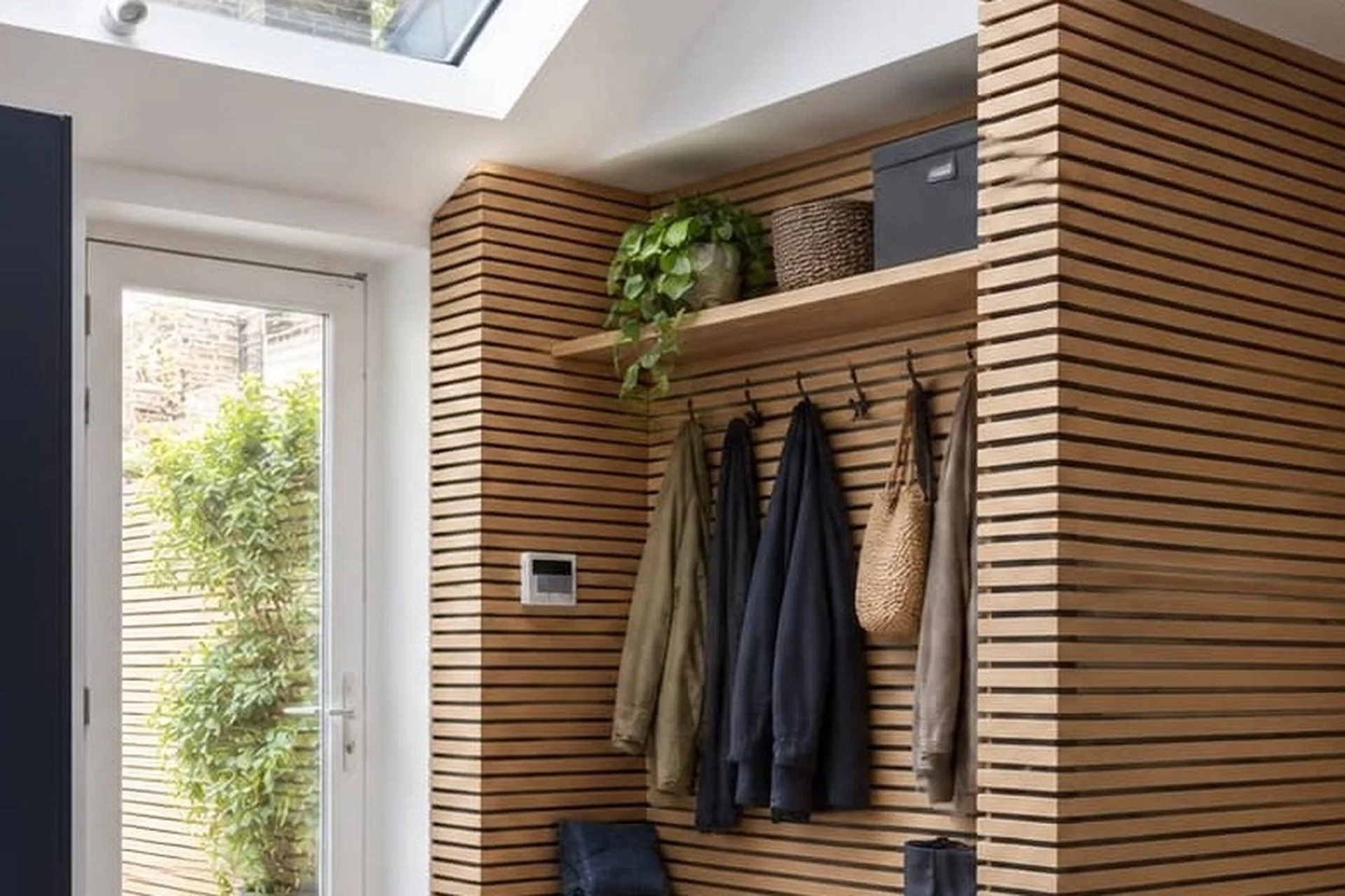 Coat hooks and open shelf in a boot room, with jackets and a bag hanging.