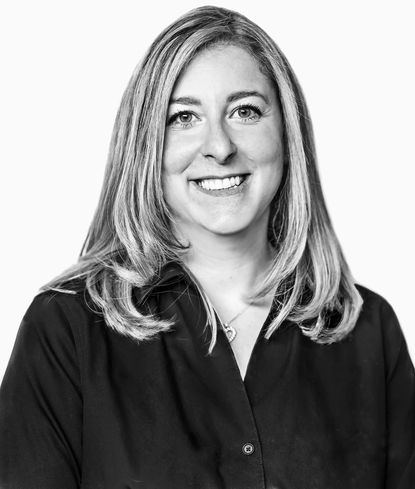 Black-and-white corporate headshot of a smiling woman with long blonde hair in a dark button-down shirt against a white backdrop