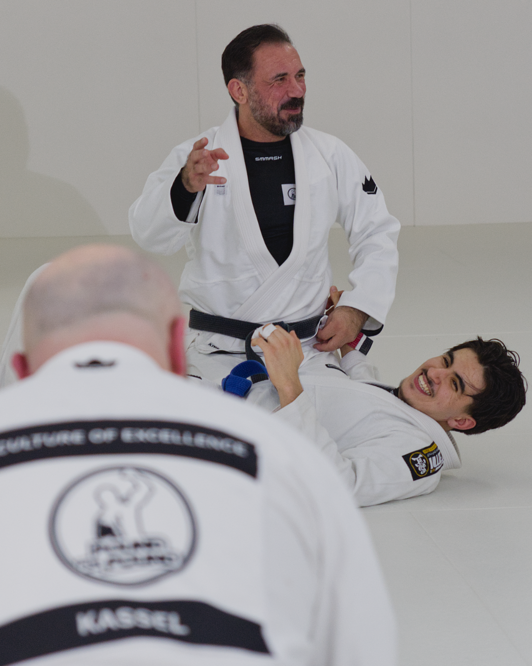 Ein Trainer erklärt eine BJJ-Technik im Gi vor der Trainingsgruppe