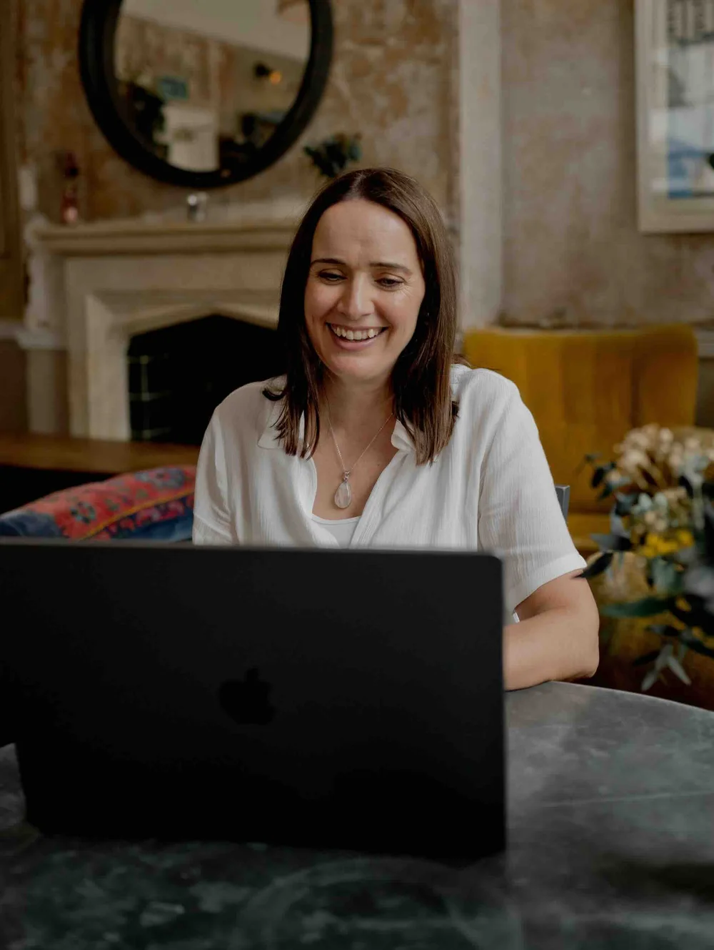 A student smiling at her laptop during a live online ADHD coach training session