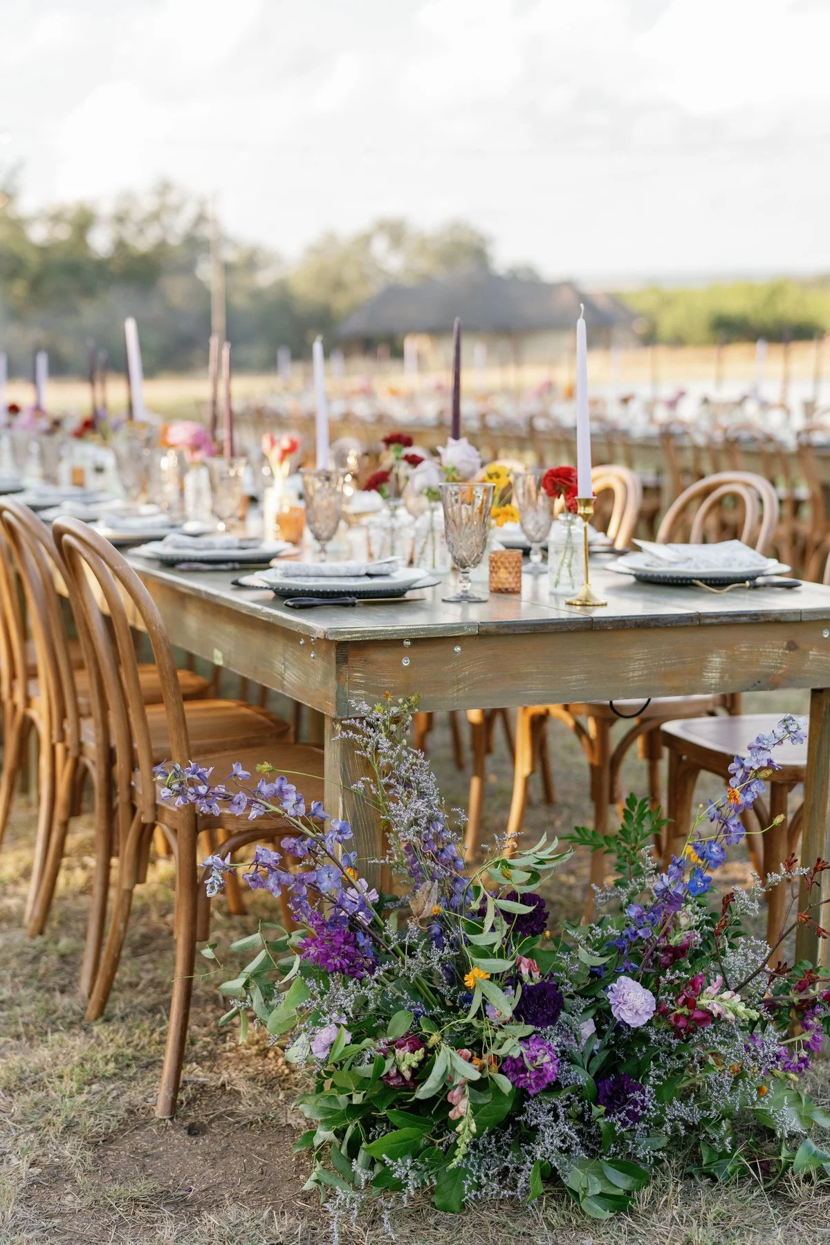 Flowers and place settings along an outdoor wedding table.