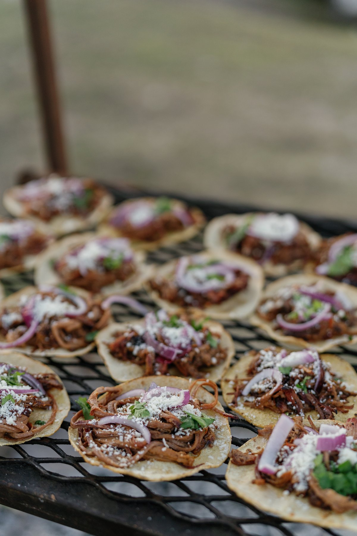 Small tacos arranged on the live-fire grill for wedding service.