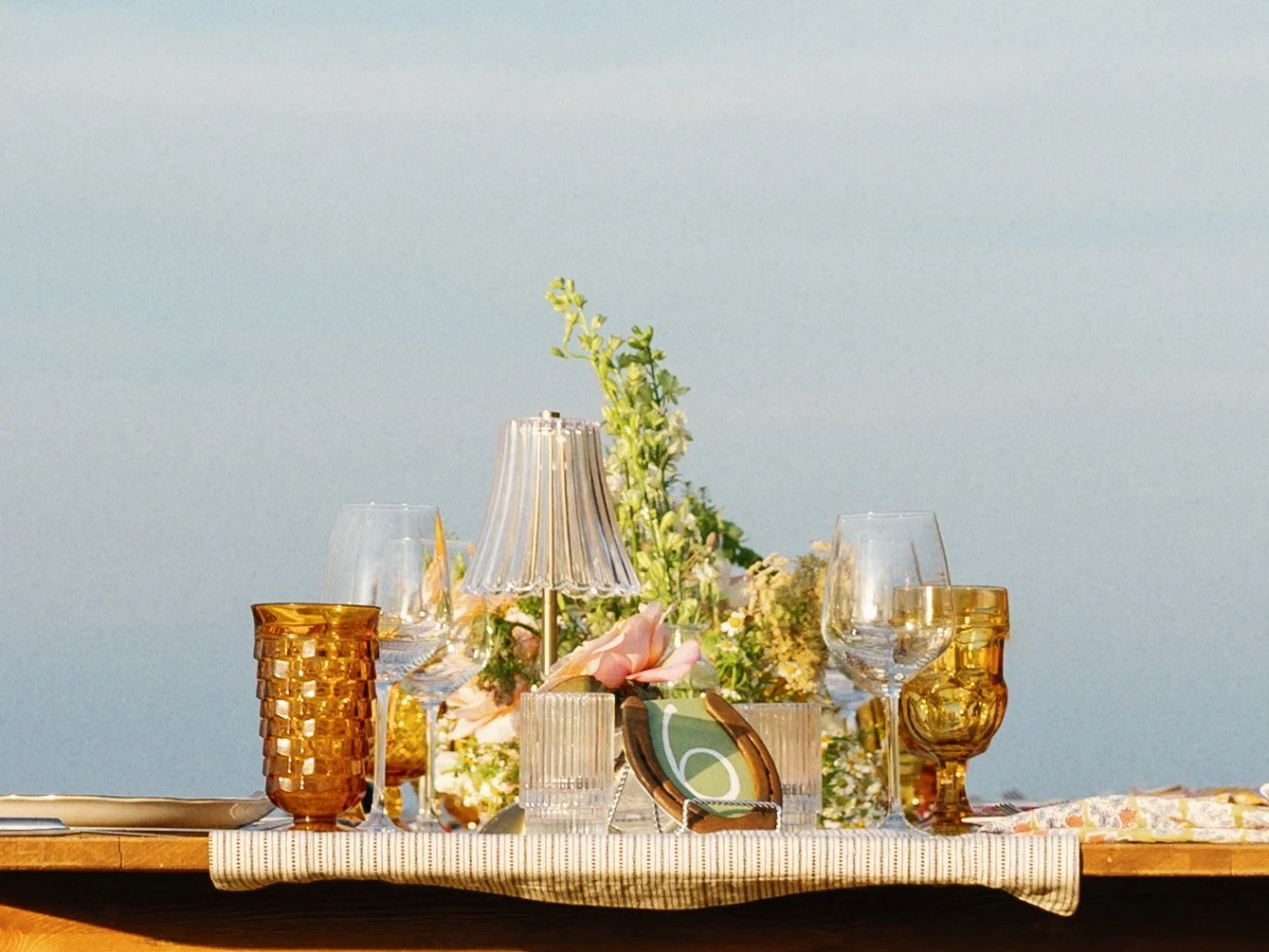 A wedding place setting with amber glassware and flowers.