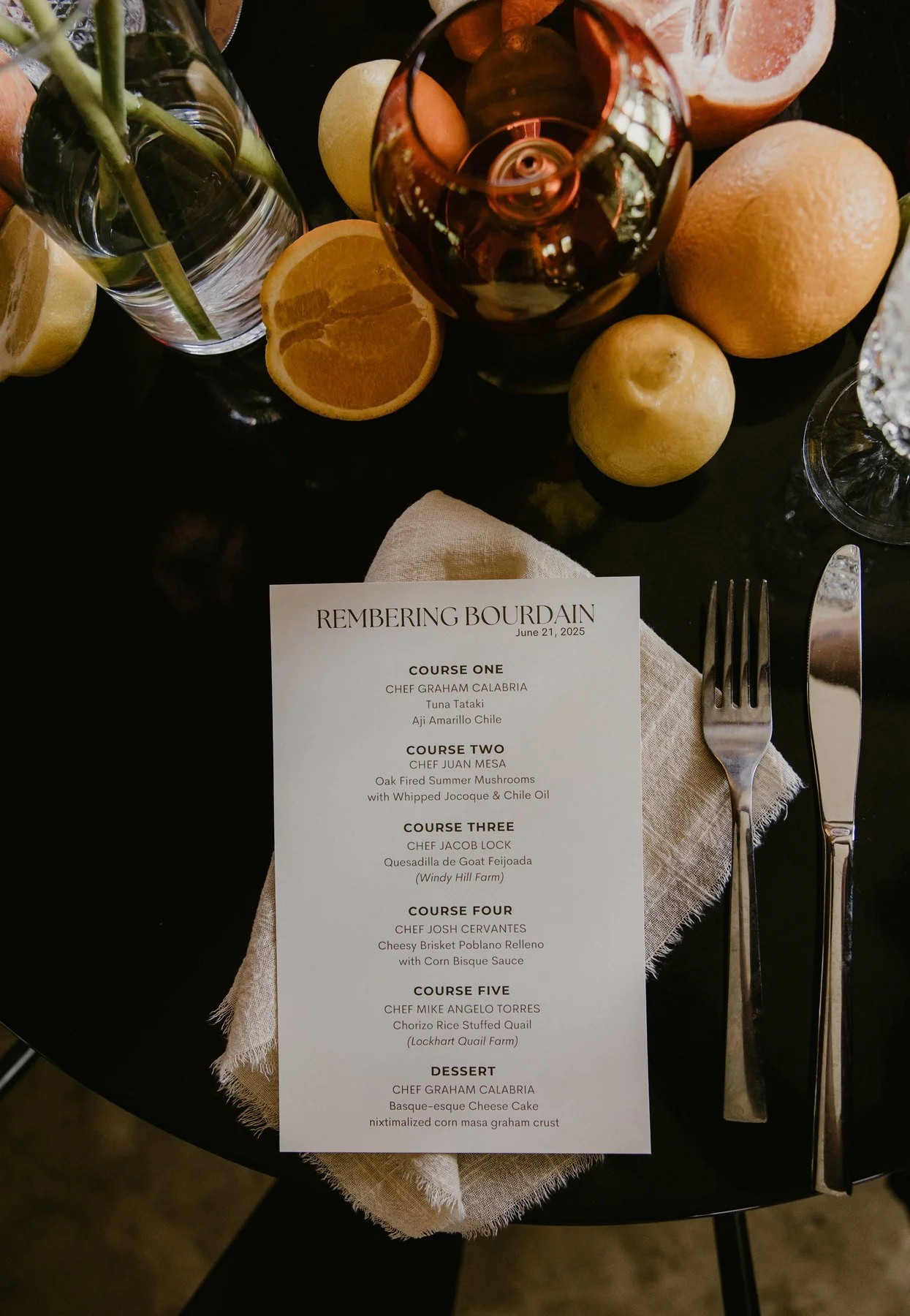 Printed Remembering Bourdain menu beside citrus and a place setting at Duett’s.
