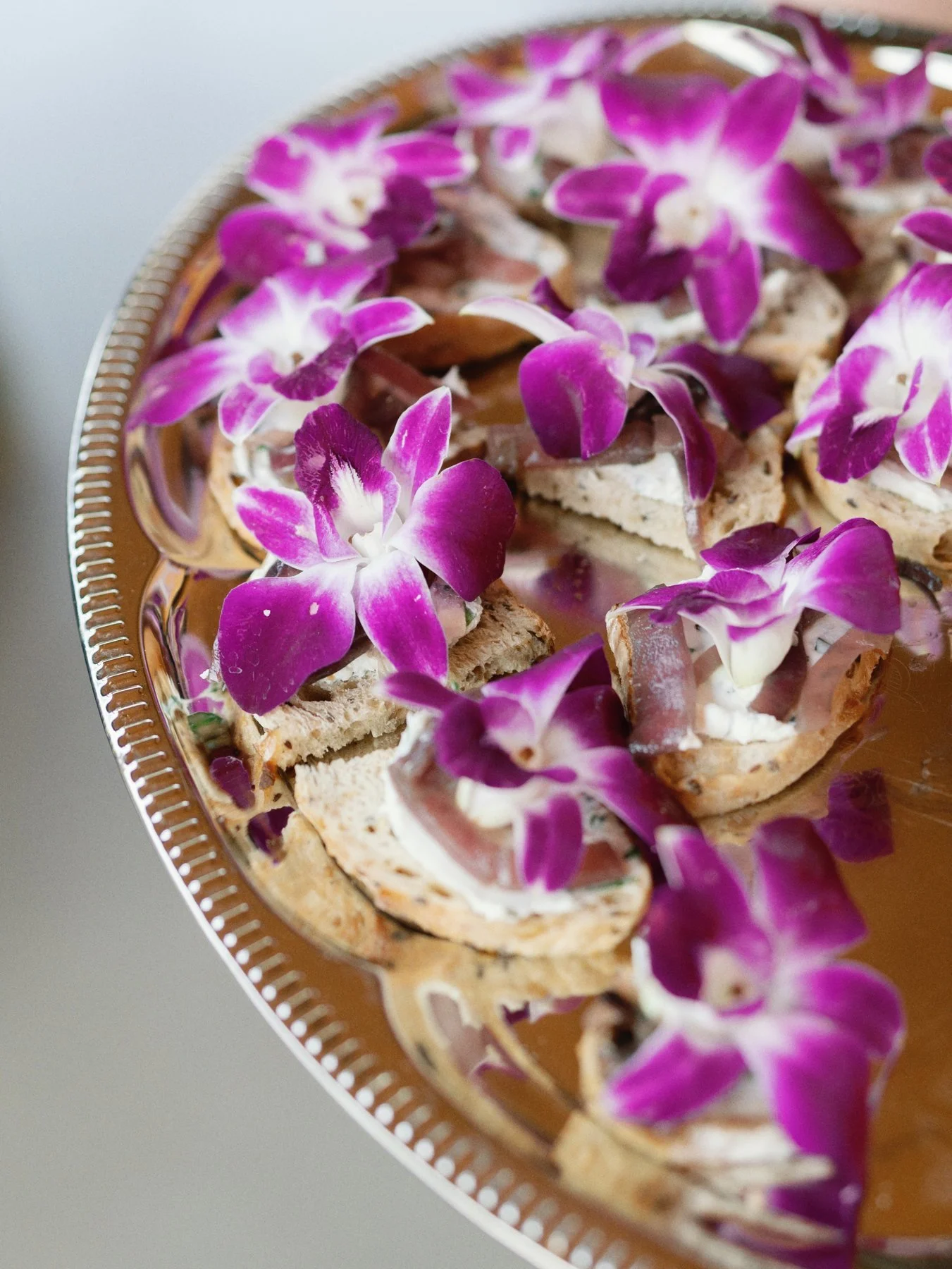 Small appetizer bites with purple orchid garnishes at Jackson and Tessa’s wedding.