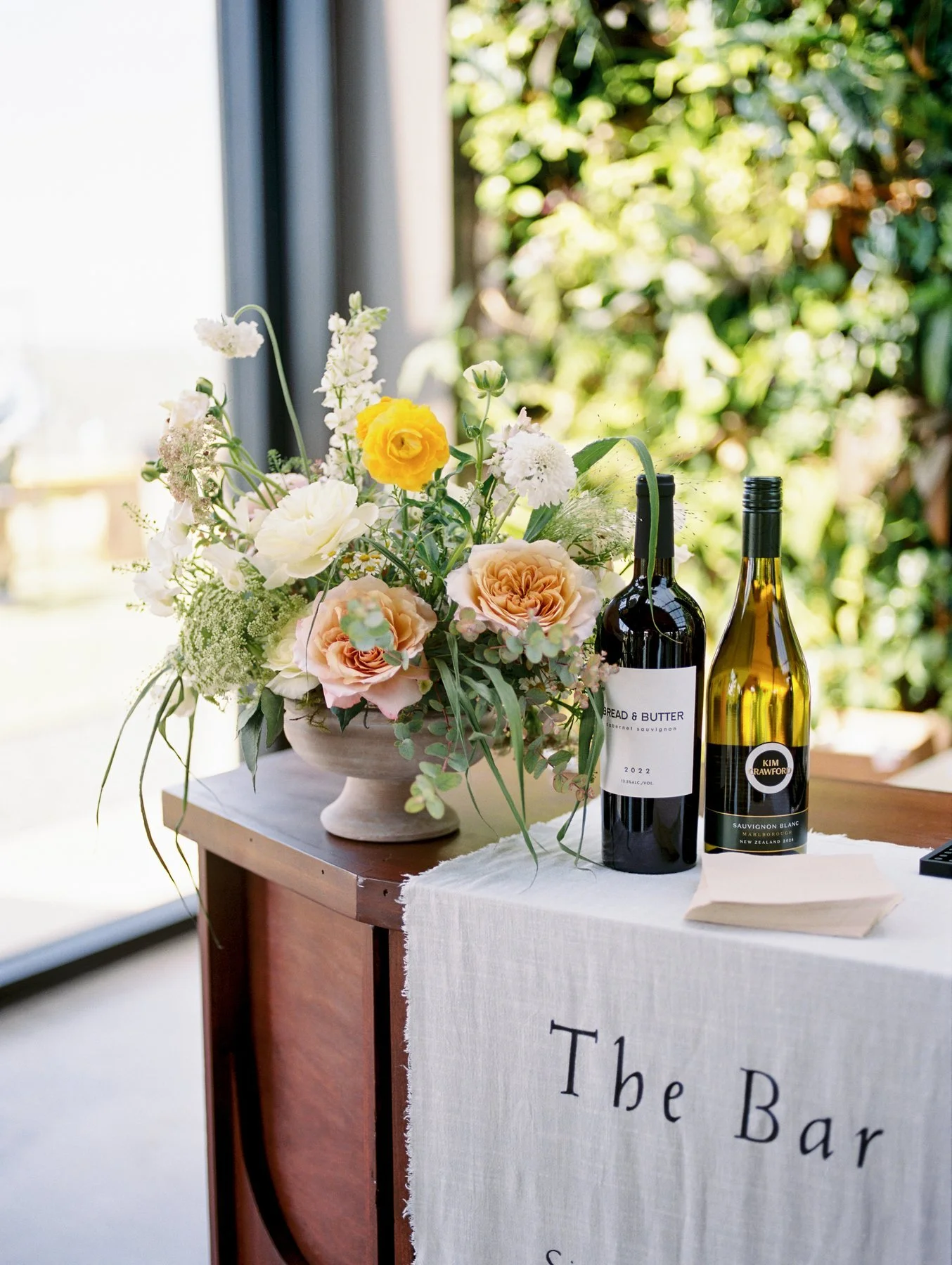 Flowers and wine bottles on a wedding bar display.