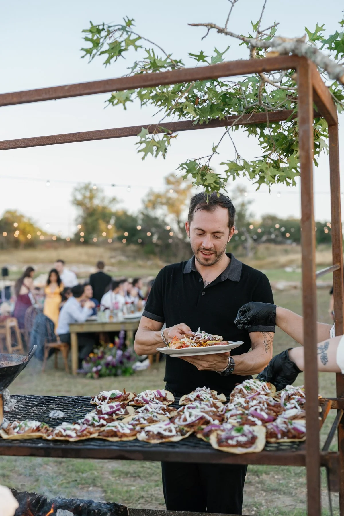 A guest with a plate beside the live-fire cooking station.